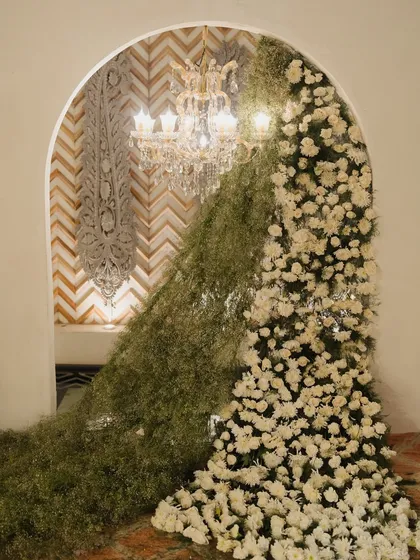 A unique floral installation where a cascade of baby's breath and white chrysanthemums flows through an archway. This is an example of the artistic and unexpected decor elements I love to create.