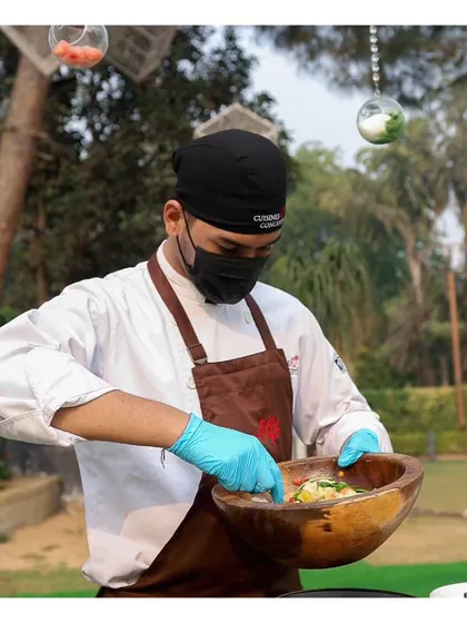A chef tosses a fresh salad in a large wooden bowl. Our live salad bars offer a variety of greens, toppings, and dressings for a healthy and customized option.