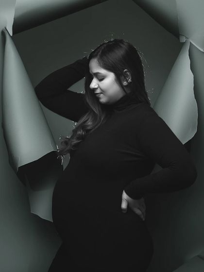 A creative "breaking through" concept. This artistic black and white photo shows the mother-to-be emerging from a paper background, symbolizing new beginnings.
