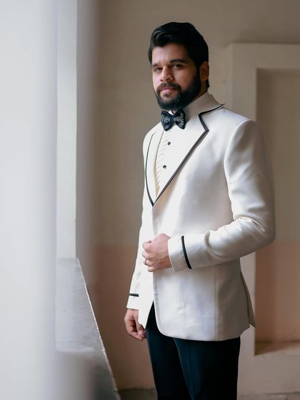 A classic, confident portrait. The black piping on the white jacket provides a sharp, modern contrast.