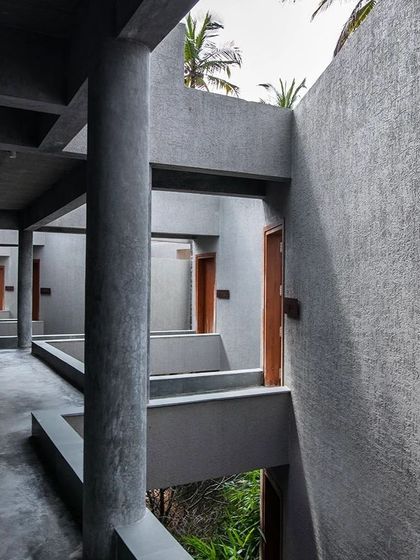 The corridors of the Anahaspa retreat are defined by a rhythm of raw concrete columns and voids. This creates a porous boundary that frames views of the lush landscape, inviting a sense of tranquility and connection to the outdoors.