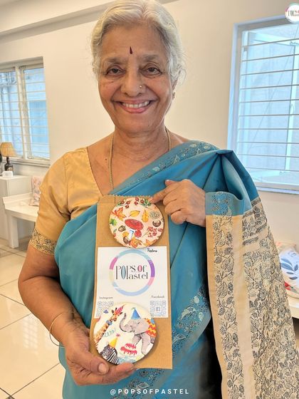 A guest at a baby shower proudly displays the beautiful decoupage coasters she made as a gift for the mom-to-be.