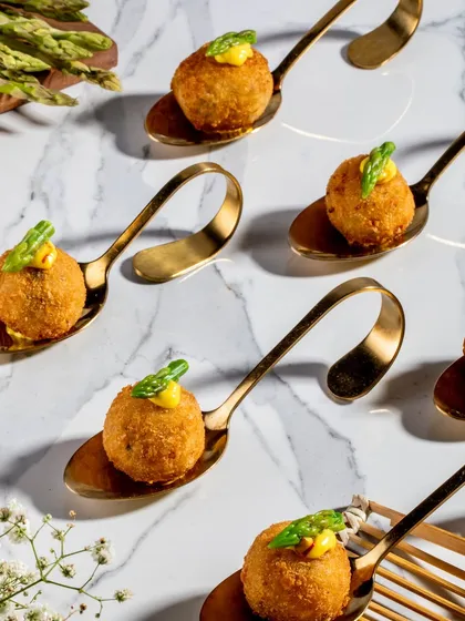Creamy wild asparagus and edamame arancini balls, fried to a perfect golden brown and served on elegant spoons with a dollop of saffron aioli.