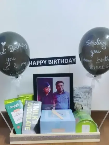 A simple and elegant birthday hamper with a framed photo, chocolates, and balloons with handwritten messages. It's a thoughtful way to send birthday kisses and good wishes from afar.