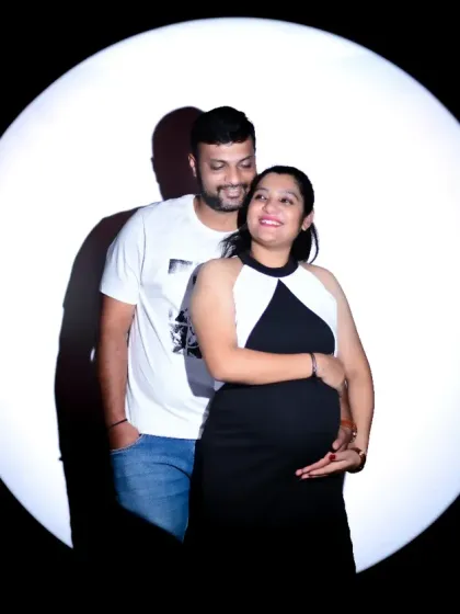 I love including partners in the photoshoot to capture the shared joy of this special time. This dramatic spotlight portrait is a great example of how I create artistic and intimate images for couples, focusing on your connection and anticipation.