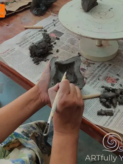 A close-up of hands using a tool to carve into a clay sculpture. This shows the detailed work and focus that goes into creating even a simple form.
