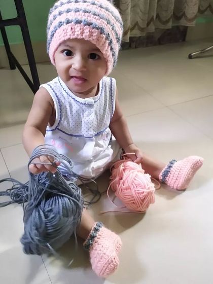 A playful moment with the yarn used for the Dewdrops beanie and booties set. It shows how soft and fun these handmade items can be for little ones.