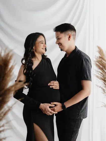 A beautiful portrait of the parents-to-be. They chose matching black outfits for a sleek, modern look in the studio, and the pampas grass adds a soft, textural element to the background.