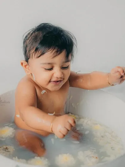Playing with flower petals in the water, this little one is having the time of his life.