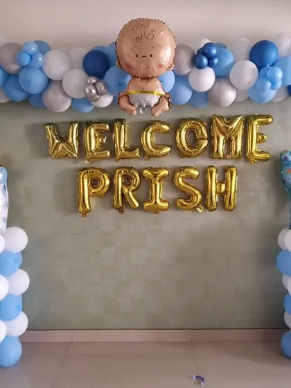 A personalized 'Welcome Prish' decoration for a baby boy, with balloon pillars, a balloon garland, and custom name foil letters.