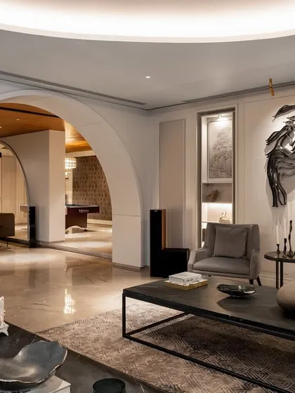 Another view through the arched openings, showing the transition from a formal seating area to the entertainment lounge with a pool table in the background.