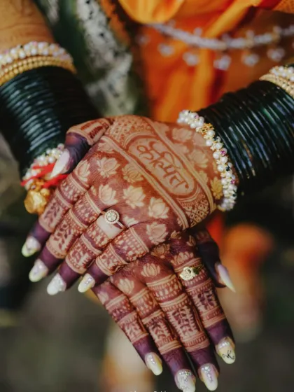 The beautiful dark stain on this Maharashtrian bridal mehendi highlights the groom's name 'Kunal' written in a traditional font on the palm.