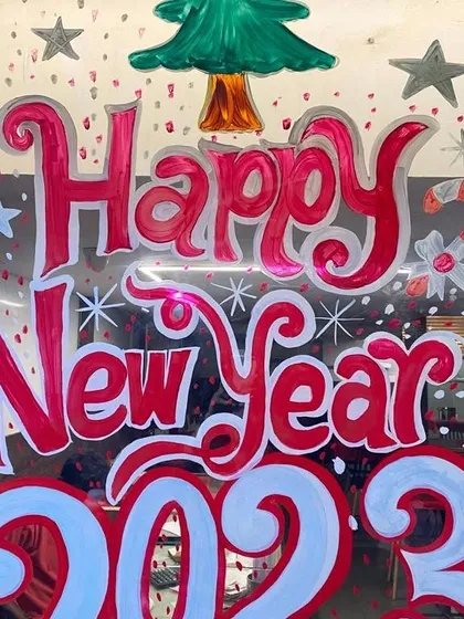 A 'Happy New Year 2023' glass painting, complete with a Christmas tree and candy cane details. This is a great way for businesses to transition from Christmas to New Year celebrations.