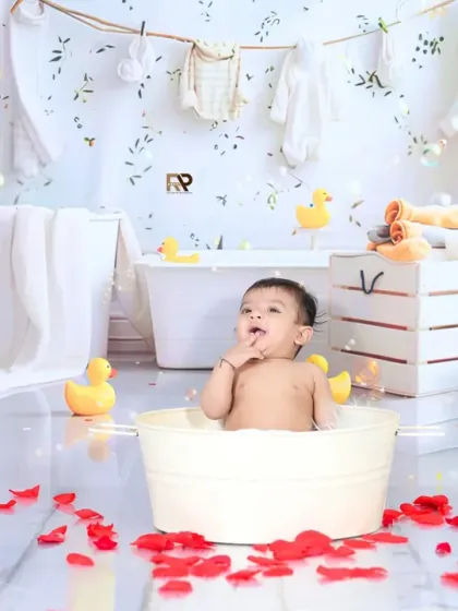 Another view of the half-birthday splash session, capturing the baby's curious expression. The setup includes yellow roses and rubber ducks for a bright and happy feel.