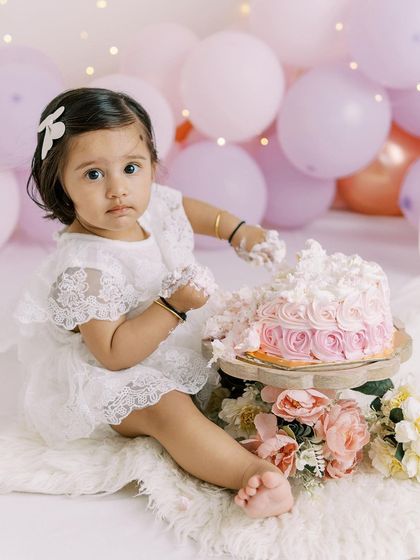 A little girl curiously inspects her birthday cake before digging in. These moments of anticipation are just as precious as the smash itself.