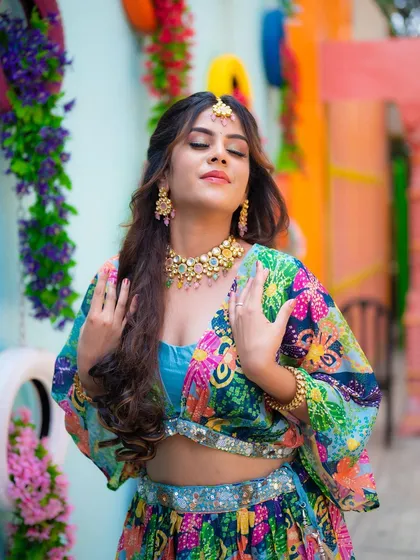 A portrait of a model in a vibrant Mehendi outfit, with her eyes closed as if making a wish. The colorful background adds to the festive and dreamy atmosphere.