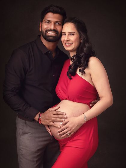 A joyful and confident portrait of the couple. Their hands together on the baby bump symbolize their partnership in this journey.