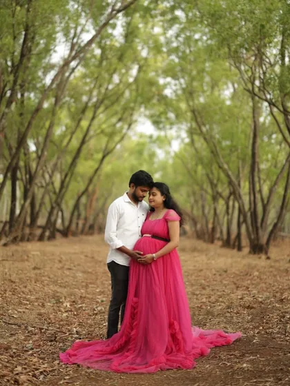 A romantic walk in the woods. This couple's maternity shoot is made more magical with our pink trail gown, which flows gracefully behind them.
