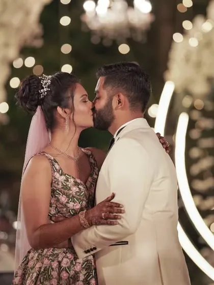 A romantic kiss seals the deal. This beautiful moment, captured against a backdrop of twinkling lights, is the perfect end to a fairytale wedding ceremony.