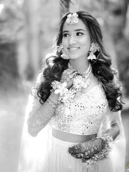 Another stunning black and white photo, focusing on the bride's smile and the delicate floral earrings and maang tikka we created for her.