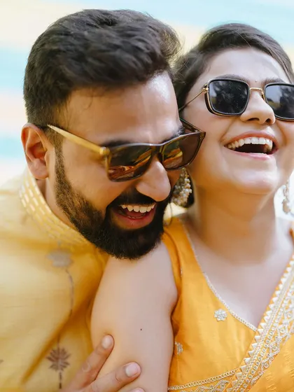 Pure laughter and joy captured during a Haldi ceremony. The sunglasses add a fun, modern twist to the traditional event.