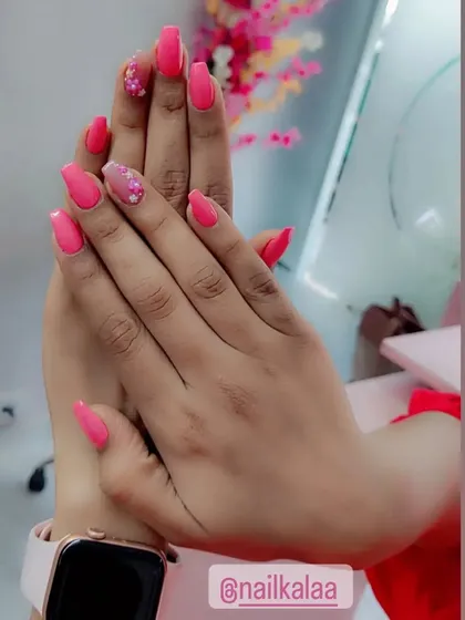 A lovely solid coral pink manicure with accent nails featuring encapsulated glitter and dried flowers.