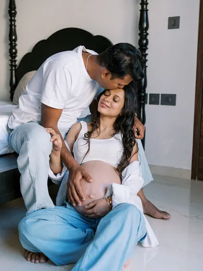 A beautiful, tender moment on the floor of their bedroom. The partner's gentle kiss on her forehead speaks volumes about his love and care for her and their coming baby.