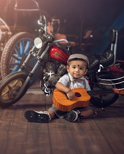 Rockin', rollin', and totally ruling the cute lane. This little musician is ready for his concert with his guitar and a vintage motorcycle backdrop.