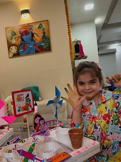 A young artist shows her colorful hands during our Holi celebration. We believe in getting messy and having fun while creating.