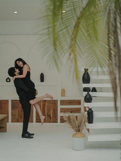 A classic romantic lift, framed by the clean, modern lines of this indoor studio space. The palm leaves add a touch of softness and nature.