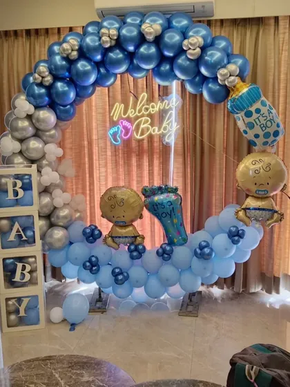 A "Welcome Baby" boy setup with a blue and silver balloon ring, neon sign, and "BABY" blocks.