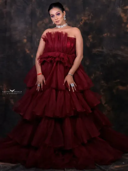 A full-length shot showcasing the grand, multi-layered silhouette of the red fashion gown.