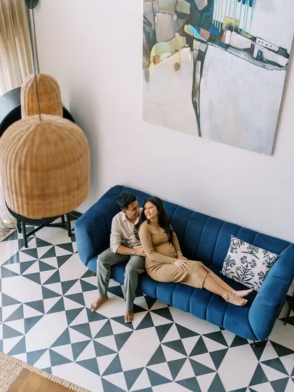 An overhead shot of the couple relaxing on their stylish blue sofa. This perspective gives a great view of their living space and their comfortable, easy connection.