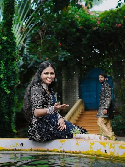 A playful moment by the fountain, with the water adding a dynamic element to the photo.