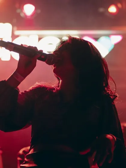 A close-up, moody shot from the TS Collective show at Fandom. The red lighting and intense focus capture the artistic and emotional depth of the performance.
