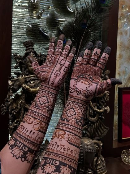 A full-arm baby shower mehendi with extensive detail. It tells a story with elements like a baby in a cradle, elephants, and other celebratory symbols extending all the way up the arm.