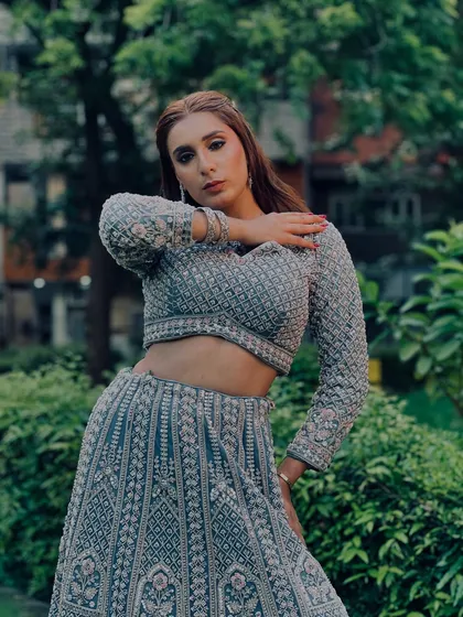 An outdoor shot of a model in our stunning grey lehenga. The full-sleeve blouse and heavy embroidery make it a very sophisticated choice.