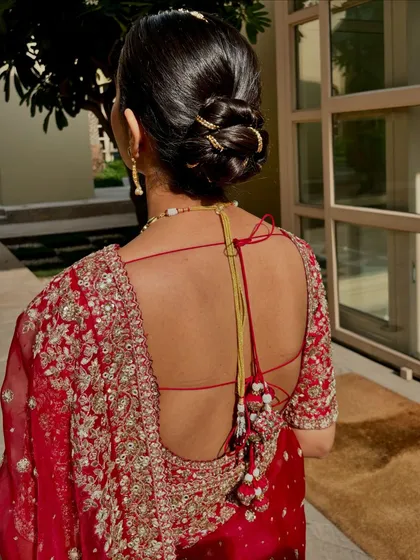 A look at the classic bridal bun. This hairstyle is not only elegant but also practical, keeping the focus on her beautiful backless blouse and jewelry.