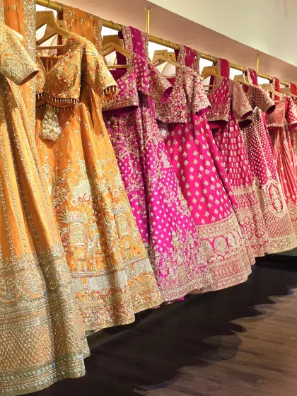 A rack of our curated lehengas, showcasing the spectrum of colours and craftsmanship available. From deep jewel tones to warm oranges and bright pinks, each piece is waiting for its moment.
