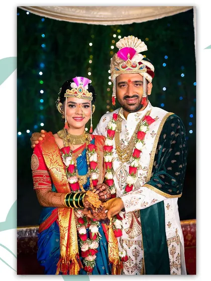 A classic portrait of the bride and groom in their full Maharashtrian wedding attire. They stand together, showcasing the intricate details of their outfits against a beautifully lit backdrop.