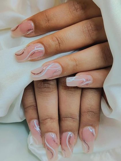 An elegant design on long square nails, featuring a sheer pink base with delicate swirls of white and rose gold glitter.