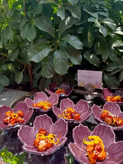 Honey chilli potato bites served in beautiful purple flower-shaped bowls, part of a larger, vibrant buffet spread.
