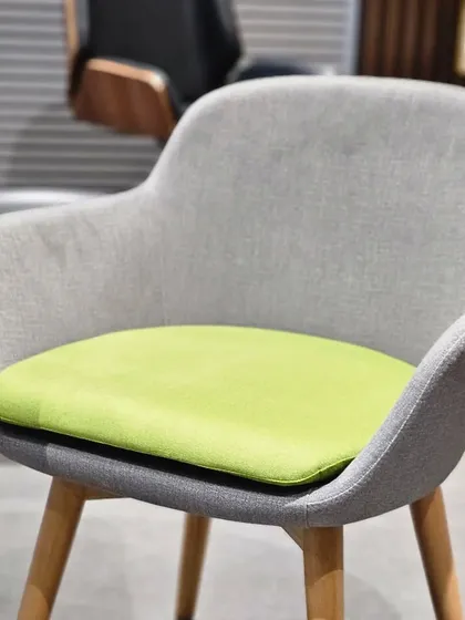 A simple yet stylish armchair with a grey fabric body and a bright lime green seat cushion for a pop of color. The wooden legs add a touch of warmth.