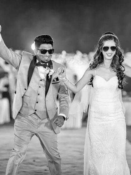A high-energy black and white shot of the couple's reception entrance. Their fun sunglasses and dynamic poses show off their personalities.