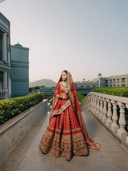 A full-length shot of Divya on a bridge at Raffles Udaipur. The composition uses leading lines to draw the eye to the bride, emphasizing her elegance against the palatial setting.