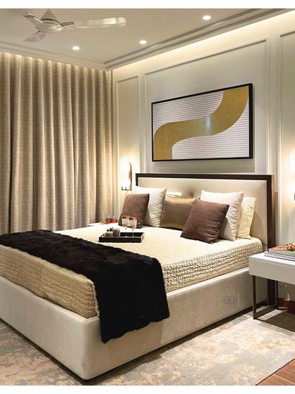 The bedroom in the DLF apartment features a calm and soothing color scheme. Wall paneling adds a classic touch, while the abstract artwork provides a contemporary focal point above the bed.
