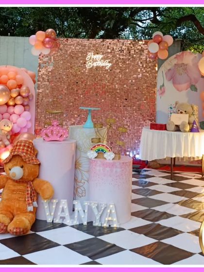 An outdoor teddy bear-themed first birthday. This setup features a checkered floor, a rose gold sequin wall, and adorable teddy bear props.