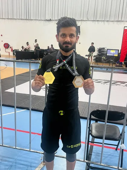 Displaying the hardware. Our competitor showing off his gold and silver medals after a successful tournament abroad. The hard work pays off.