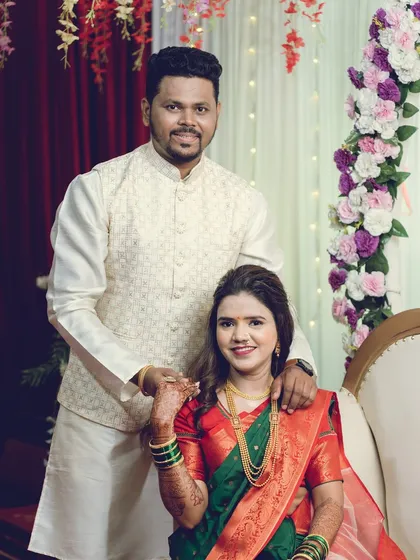 A formal portrait of a newly engaged couple, with the bride-to-be seated, showcasing her traditional saree.