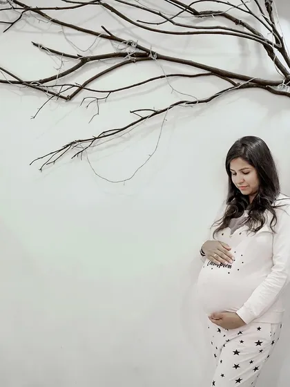 A quiet, candid moment at home. This expecting mother in cozy pajamas reflects the comfort and intimacy of our in-home maternity shoots, where you can be completely yourself.